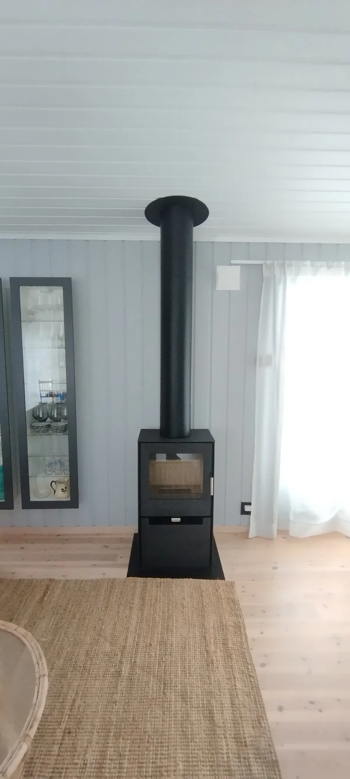 Liten vedovn montert på hytte med isolert stålpipe og stålplate på gulv