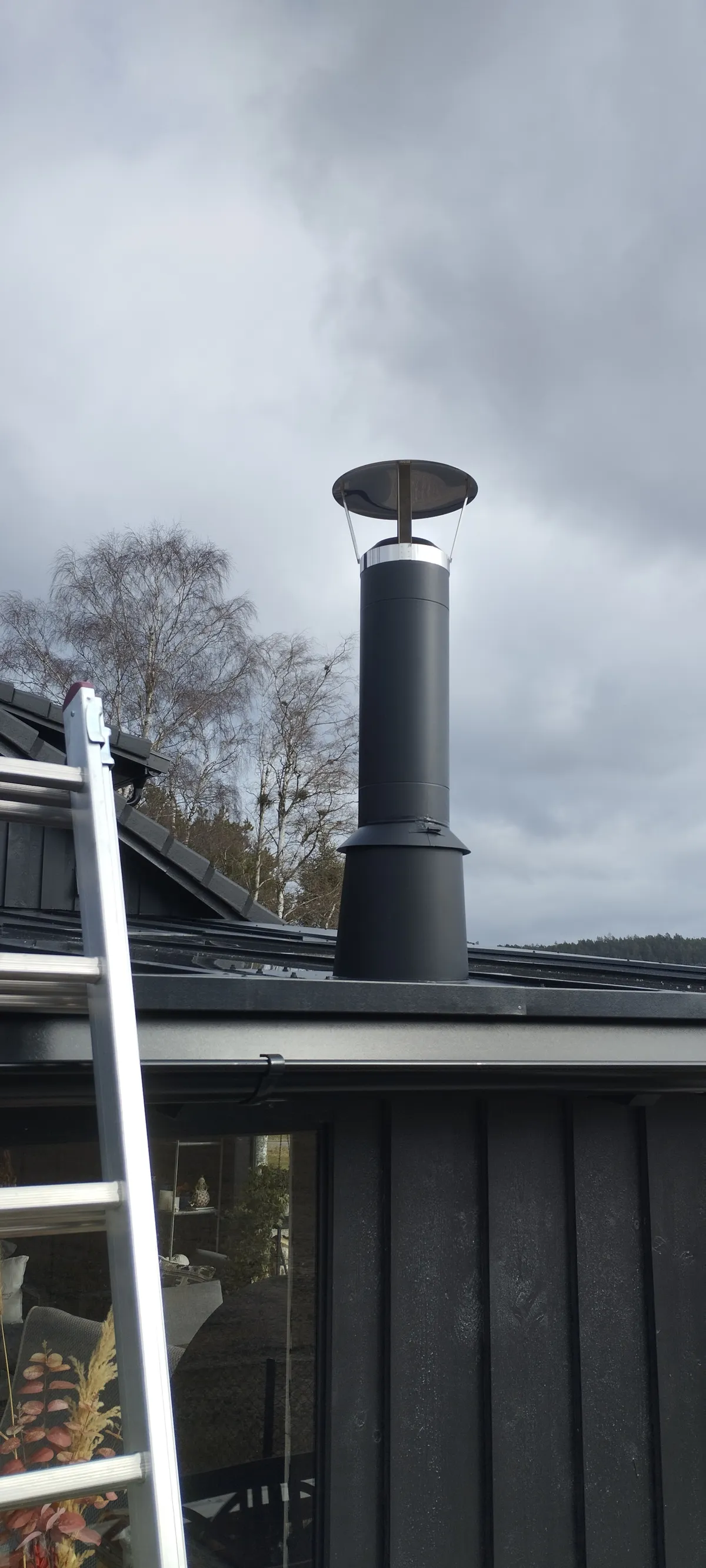 Rund stålpipe over tak på utehus